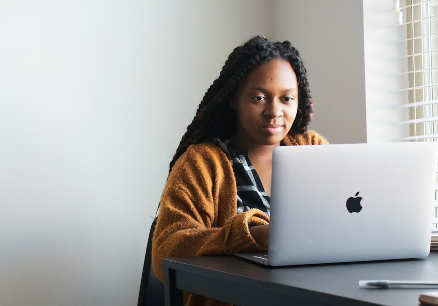Woman with braids works on a laptop at her desk