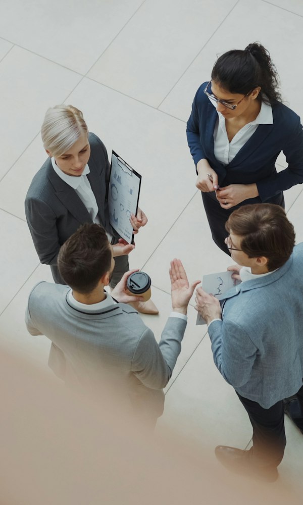 Four business people talk in an office lobby